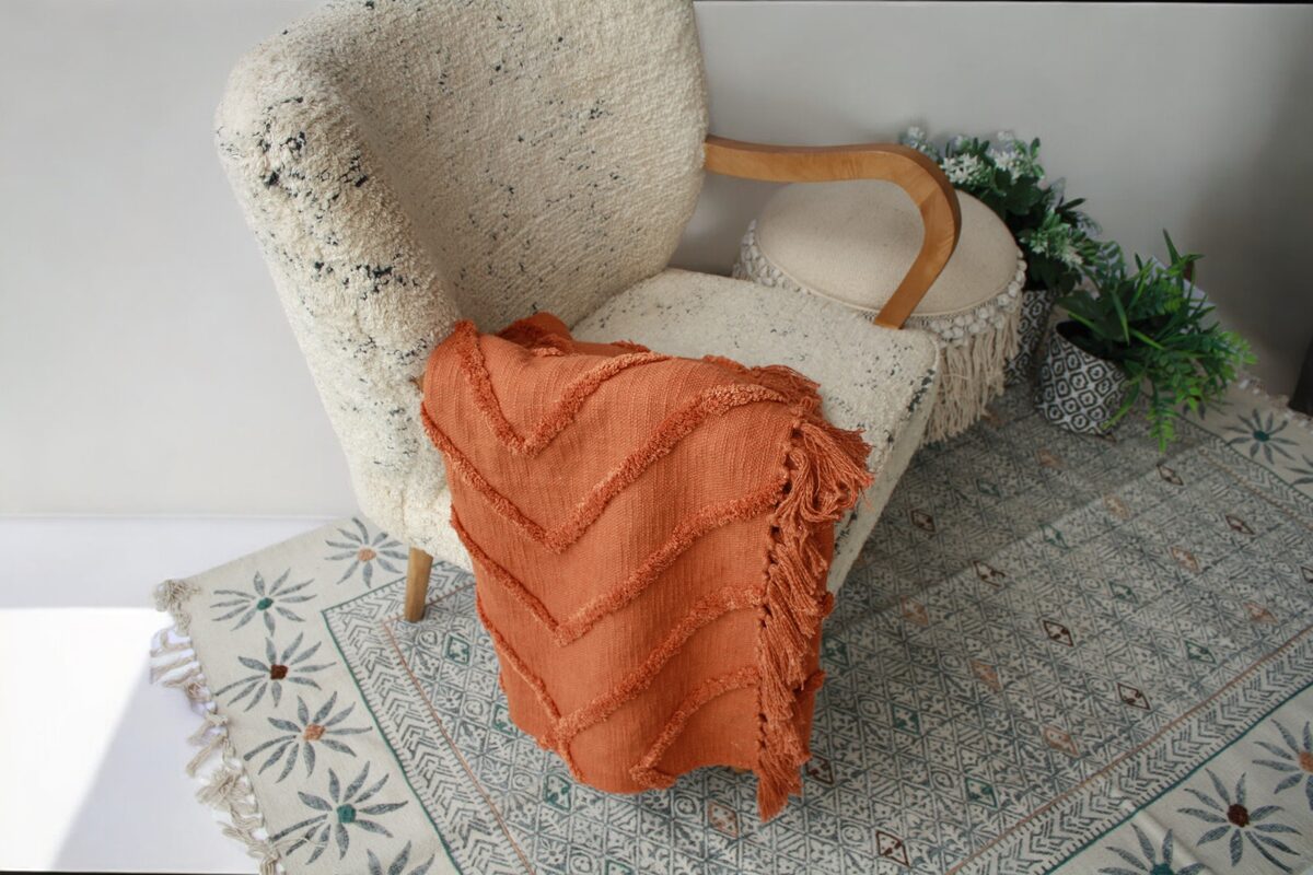 Rust throw with fringe on a cream armchair